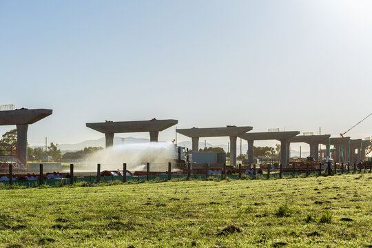 Water spraying truck dampening down ground to minimize dust on construction site