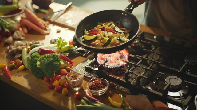 Dynamic shot of an unrecognizable chef is tossing vegetables on frying pan at professional kitchen. High quality 4k footage