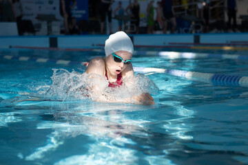 Swimmer girl swims breaststroke swimming style in the pool