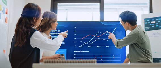 Group of Asian generation z business people work together in home office. Financial team businesspeople brainstorm meeting, use computer and presentation screen monitor. Corporate teamwork concept