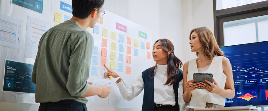 Group of Asian generation z business people work together in home office. Financial team businesspeople brainstorm meeting, use digital tablet and white board presentation. Corporate teamwork concept