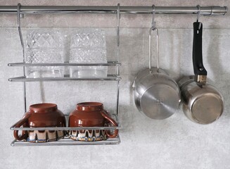 Kitchen utensils in the form of glasses, cups and coffee brewing turks hang on the kitchen wall