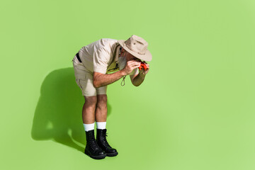 Photo of senior worker scientist look binoculars empty space wear safari suit isolated green color...