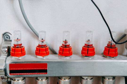 Water valve manifold with red caps aligned in a row, highlighting the intricate design. Used for efficient control and distribution of water flow in plumbing systems.