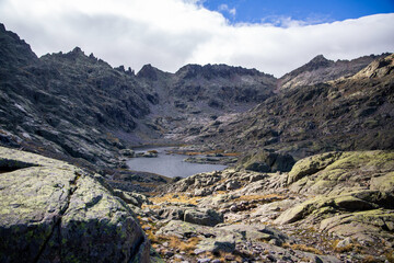 Glacial Lake Laguna Grande in Rugged Gredos Mountains Surrounded by Jagged Peaks and Rocky Terrain Under Cloudy Sky in Remote Alpine Setting