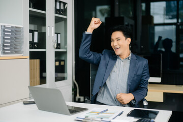 Confident businessman working on finance analysis with a tablet and laptop at office desk.