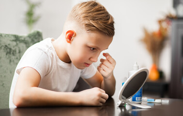 Kid teenager boy inserting contact lenses into her eye. Vision correction and ophthalmology for...