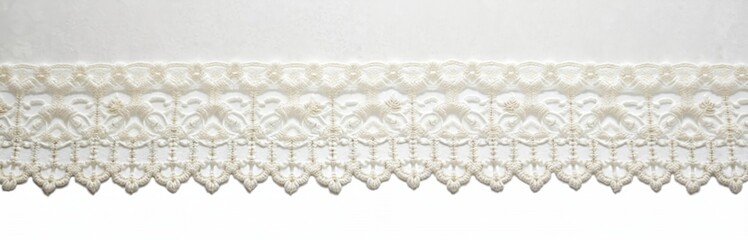 Obraz premium White cotton embroidered lace detail on white background. Delicate vintage border, decor element. Floral handmade embroidery, textile craft for design, scrapbooking.