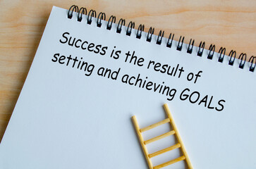 Success is the result of setting and achieving goals text on white notepad. Inspirational quote and...