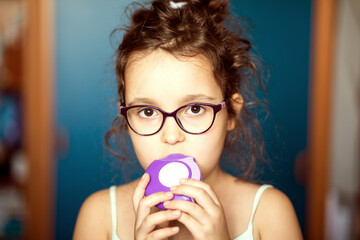 Cute little girl using asthma inhaler at home