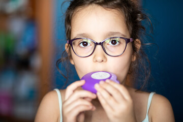 Cute little girl using asthma inhaler at home
