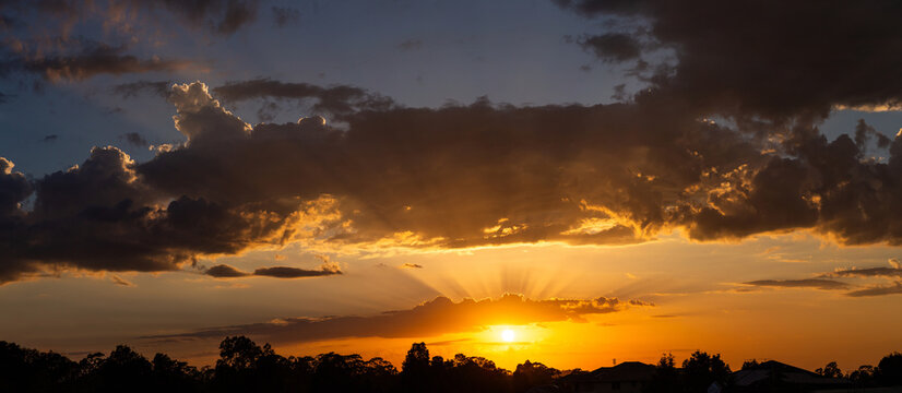 Skyscape of sun with golden rays of light from behind clouds at sunrise