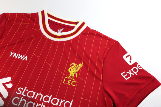 nice red soccer jersey or sports t shirt of Liverpool football club team in English premier league with club logo and Standard Chartered logo on white table after wearing, 2025 Champion Premier League