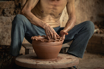 Cropped image, craftmen making pottery, elderly man in countryside sitting and making a pot from...