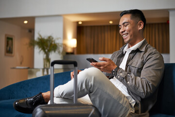 Relaxed Business Traveller in Hotel Lobby Checking Smartphone While Waiting