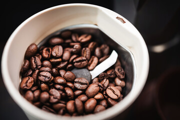 Roasted coffee beans in an electric coffee grinder, close-up view, coffee preparation