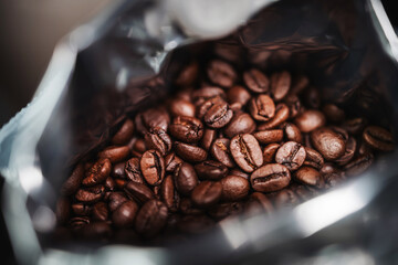 Roasted coffee beans in an opened foil bag, close-up view