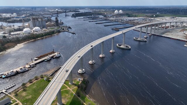 Cars crossing Elizabeth river at Norfolk Naval Shipyard in Portsmouth, Virginia showing industrial factories and other industries by the river with public park 