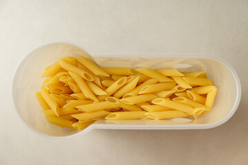 Delightful penne pasta filling a stylish white container in a modern kitchen