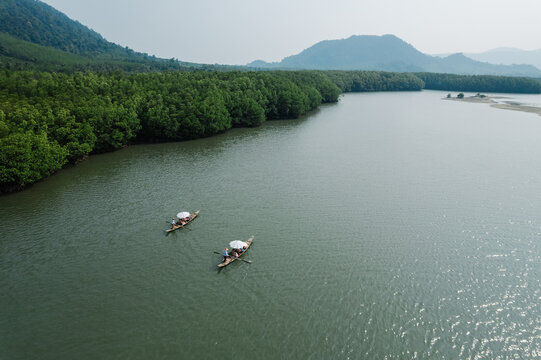 Many ancient wooden boats with rowers are traveling on the river and green forest.Nature boating, nature tourism