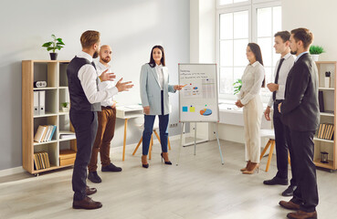 Fototapeta premium In the office setting, a businesswoman engages team in a presentation, productive conversation and collaboration among colleagues. Group meeting, teamwork and dedication to work.