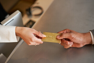 Gold Credit Card Handed Over in a Modern Reception Setting Representing Financial Transactions and Service Exchange