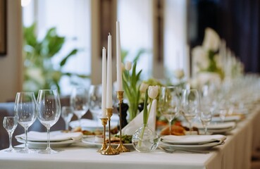 A beautifully arranged dining table featuring elegant candles, tulips, and fine glassware, perfect for an upscale gathering or celebration.