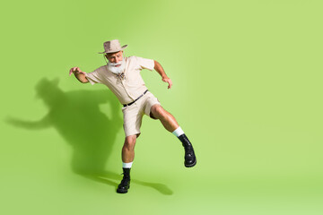 Photo of traveler senior man going carefully in jungle tour wear safari suit isolated green color background