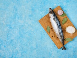 Prepared ingredients for cooking baked mackerel or other dishes from it on a wooden board on a blue...