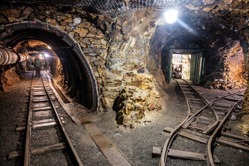 A miner navigates the dimly lit tunnels of a historic mine shaft in Jachymov, Czechia. The rustic...