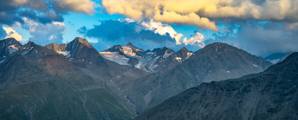 In the evening, the majestic alpine peaks are illuminated by soft light, casting dramatic shadows...