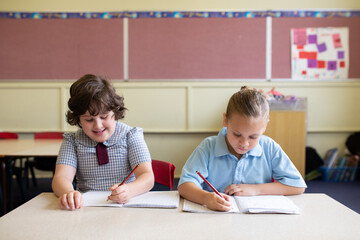 Two primary school girls sitting working in a classroom together