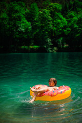 A happy teenager swims and plays in a stunning azure alpine lake. Vibrant, scenic photos capture pure joy and the beauty of nature. Perfect for travel, adventure, and summer themes. © Ekaterina