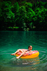 A happy teenager swims and plays in a stunning azure alpine lake. Vibrant, scenic photos capture pure joy and the beauty of nature. Perfect for travel, adventure, and summer themes.