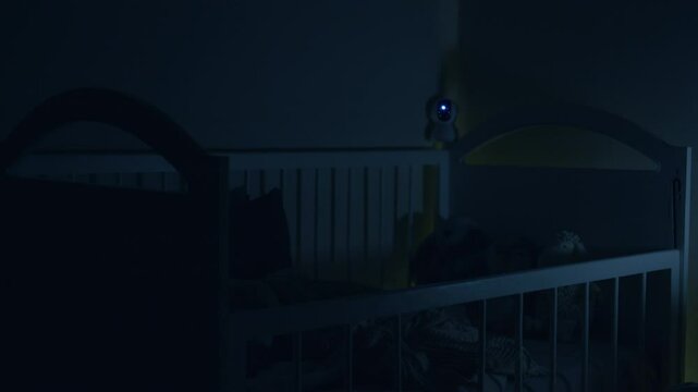 The child's room and the baby sleeps in the crib at night. Surveillance camera hanging from the baby's crib that monitors the baby.Modern digital device via wifi monitors the baby.Safety and security.