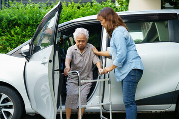 Caregiver help Asian elderly woman disability patient use walker to get in car.
