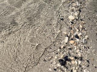calm and minimalistic image of rippling water over pebble river bottom. soothing neutral abstract texture. stone background. eco concept
