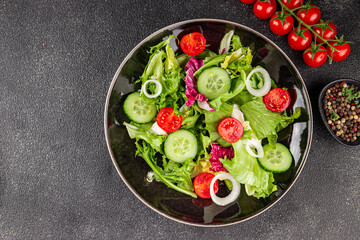 Vegetable salad tomato, cucumber, lettuce, green leaf lettuce, onion appetizer vegetable dish fresh gourmet food background rustic food top view copy space keto and paleo diet vegetarian vegan food