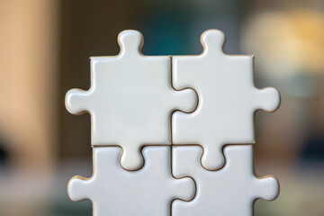 Obraz premium Close-up of white puzzle pieces fitting together, symbolizing problem-solving, collaboration, or completion in a calm, blurred background.