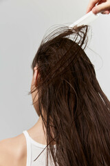 Hair care, wet hair, personal grooming A close up of a woman combing through her long, wet hair...