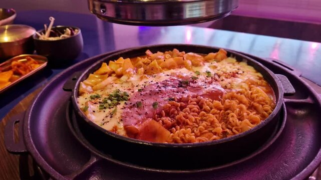 Takgalbi. Grilled patel with marinated chicken, tteokbokki, cabbage, noodles and mozzarella. Korean food. Delicious food in a restaurant. Hot food in a grilled patel