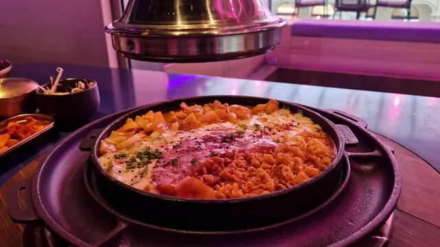 Takgalbi. Grilled patel with marinated chicken, tteokbokki, cabbage, noodles and mozzarella. Korean food. Delicious food in a restaurant. Hot food in a grilled patel