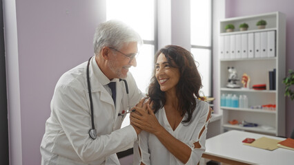 Doctor smiling with female patient in a healthcare clinic setting, highlighting a positive medical interaction indoors with a professional atmosphere.