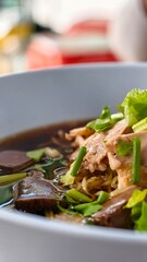 Delicious Bowl of Savory Soup with Fresh Herbs and Tender Meat Pieces