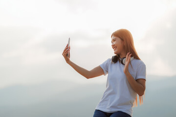 A young woman wearing a white shirt and pants is enjoying a video call with her friends, sharing...