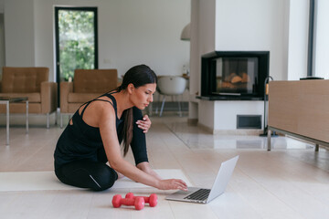 Young Beautiful Female Exercising, Stretching and Practising Yoga with Trainer via Video Call...