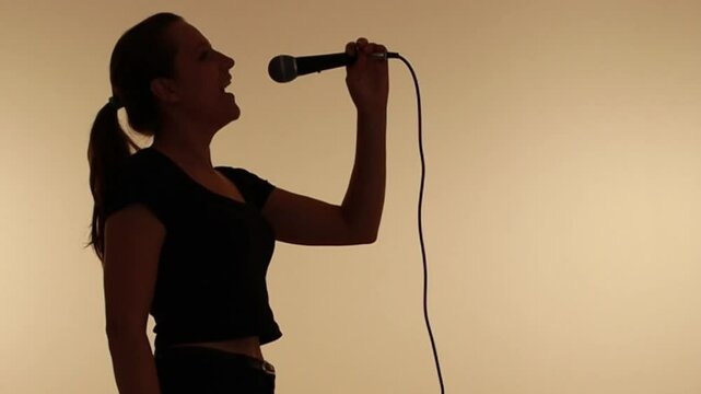 silhueta de mulher com microfone cantando 