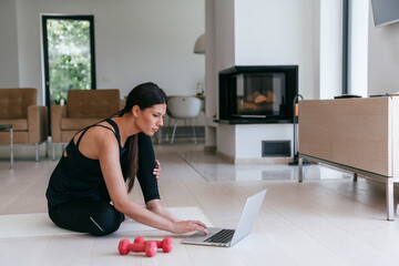 Young Beautiful Female Exercising, Stretching and Practising Yoga with Trainer via Video Call...