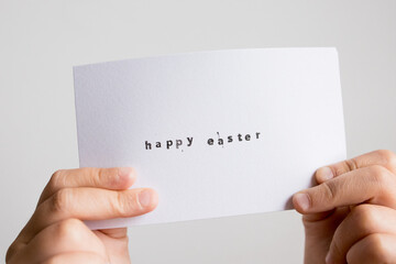 Hands holding happy Easter card with handwritten message on white background