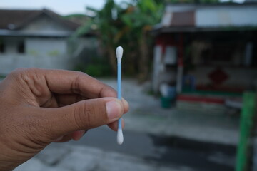 A cotton swab held in a hand